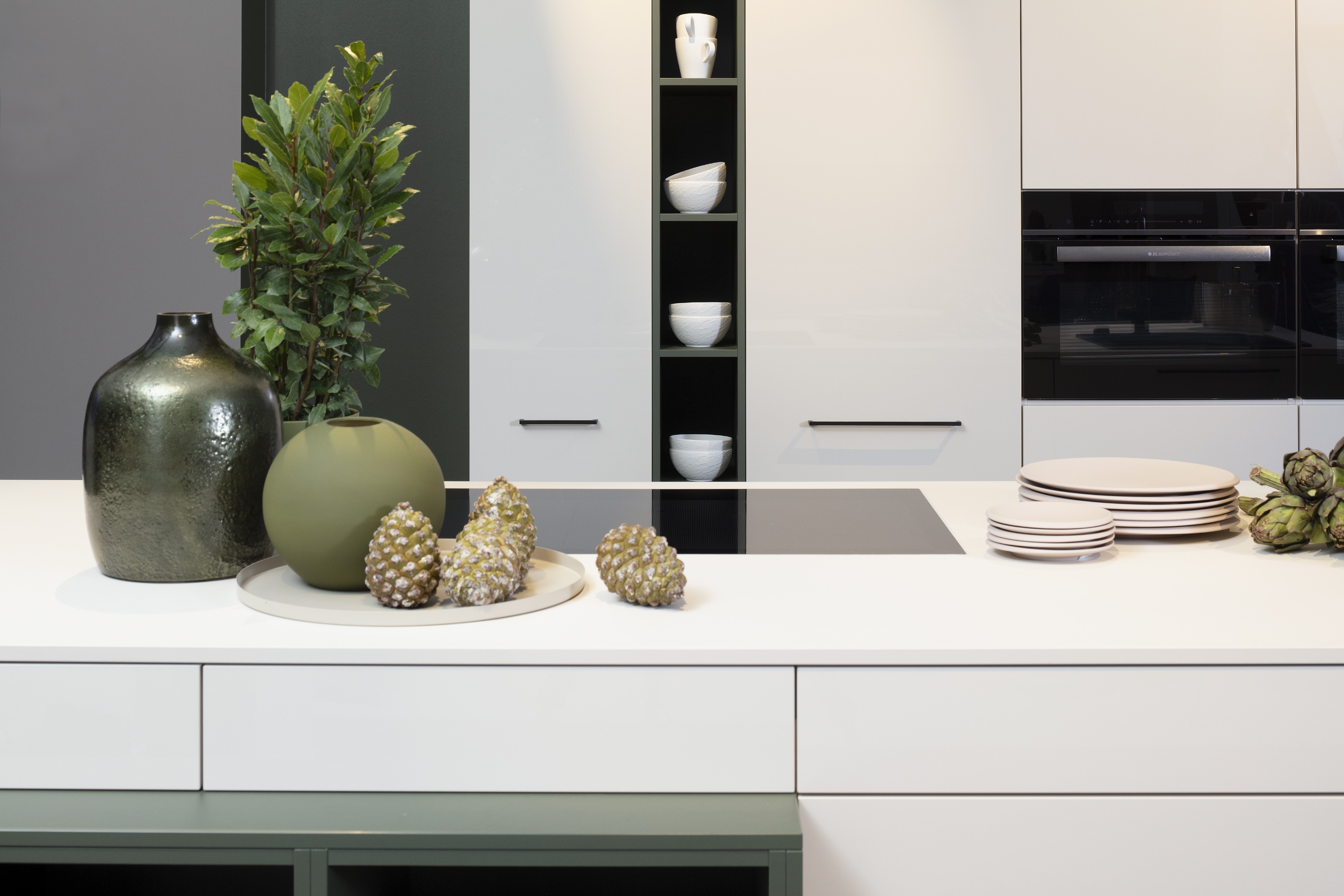 Concept130 Front: Perfect Sense Perfect Brillant Crema magnolia UV Hochglanz lackiert Front 2: Perfect Sense Scala Olivgrün Grüne Front? APL: Perfect Sense Crema Magnolia 16 mm Griff: Schwarz Metall matt Geräte: Blaupunkt Spüle und Armatur: Franke  Features: offene Regale in zweiter Frontfarbe abgesetzt, Apothekerschrank, Spüle in Schwarz.