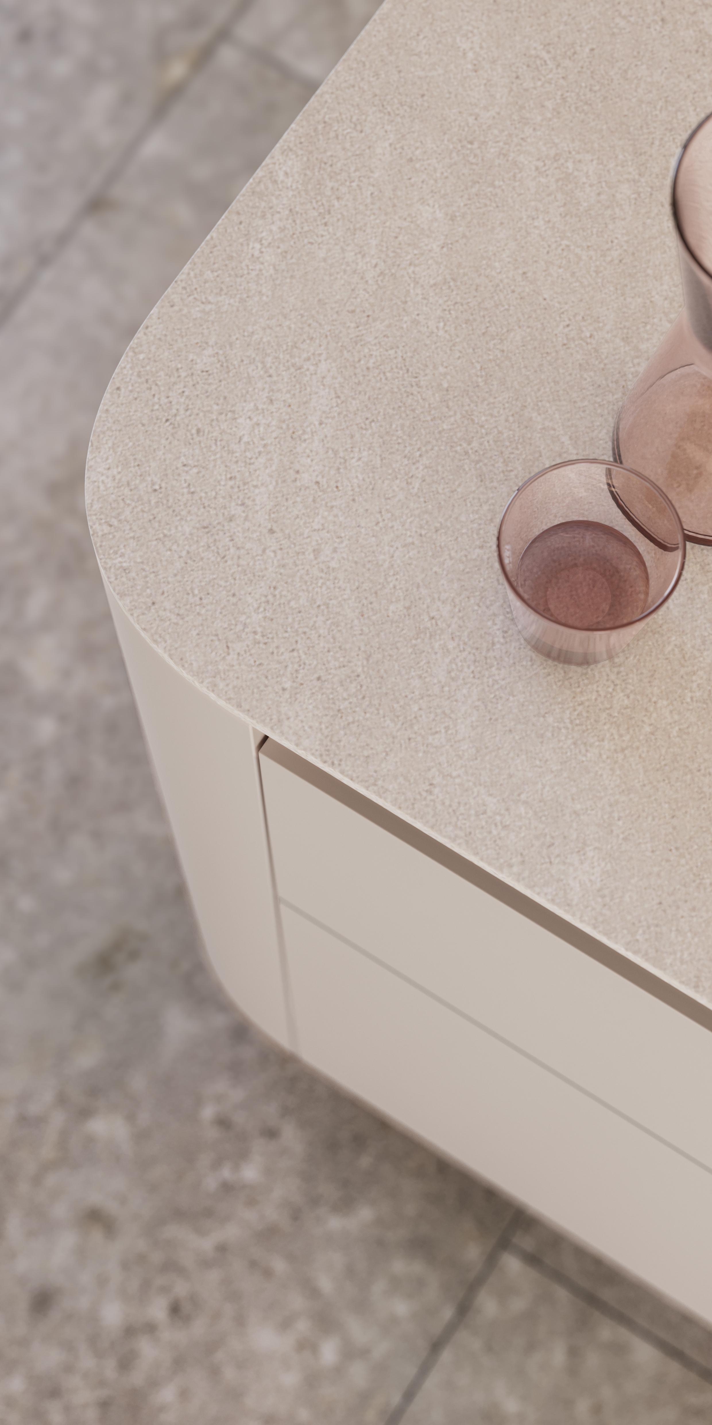 Zwei rosa Glasgefäße auf heller, abgerundeter Tischplatte.