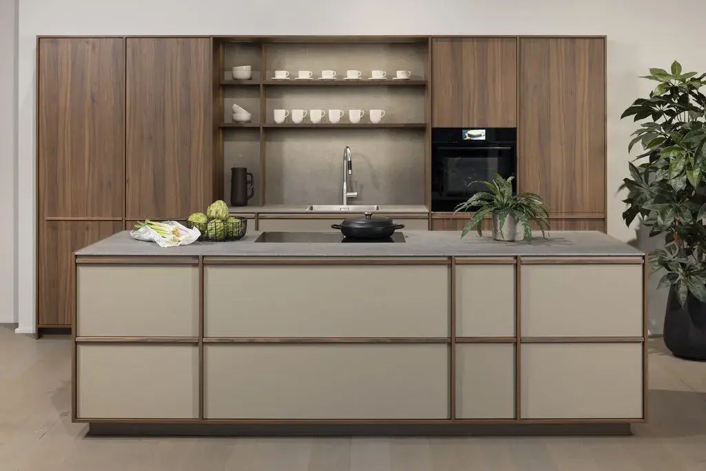 LEICHT Kücheninsel Japandi-Fronten Holzleisten auf matt lackierten Fronten sandfarben dahinter Hochschränke in Echtholz